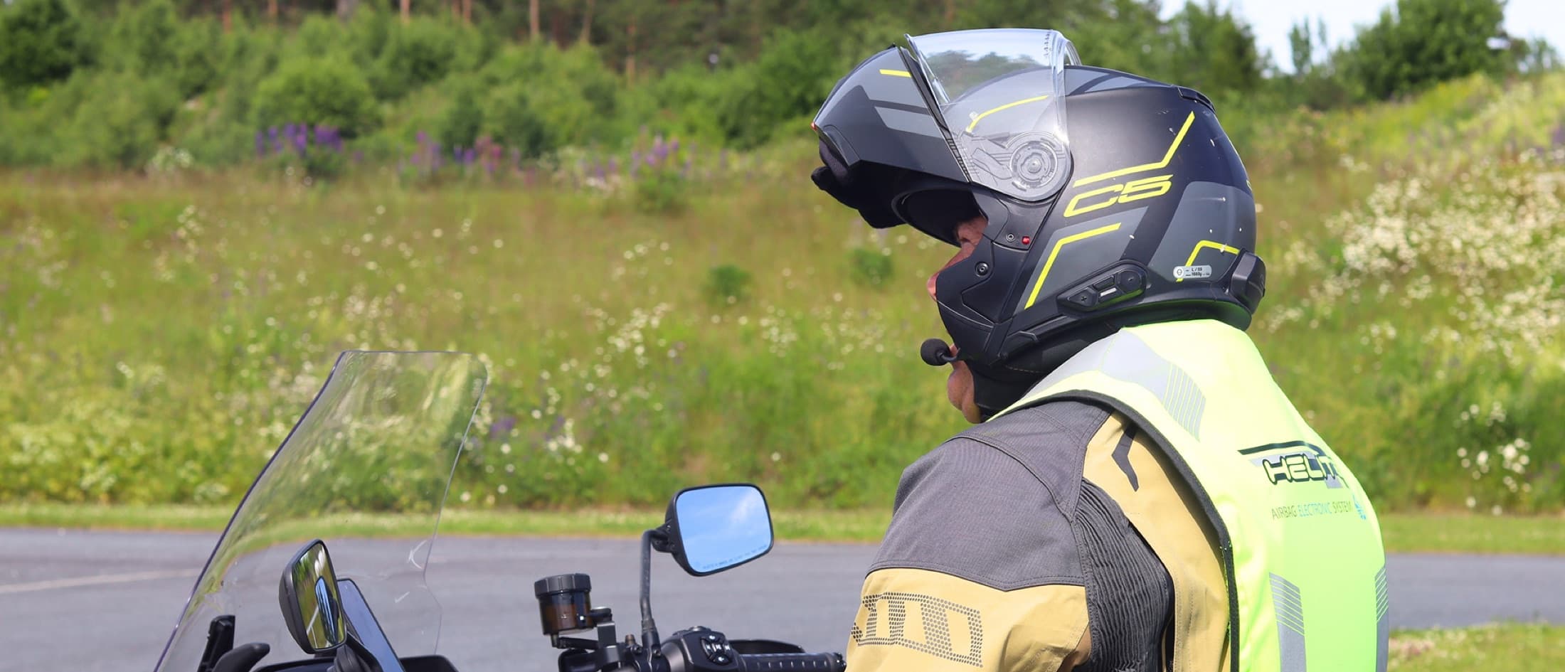 Trafikklærer på motorsykkel med åpen hjelm og refleksvest, klar for kjøretur