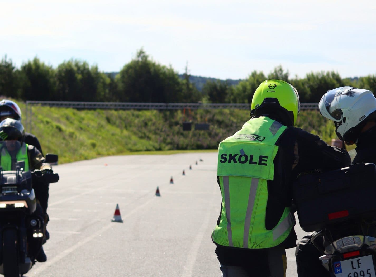 Kursdeltakere på motorsykkel med skolevest under kjøretrening på bane