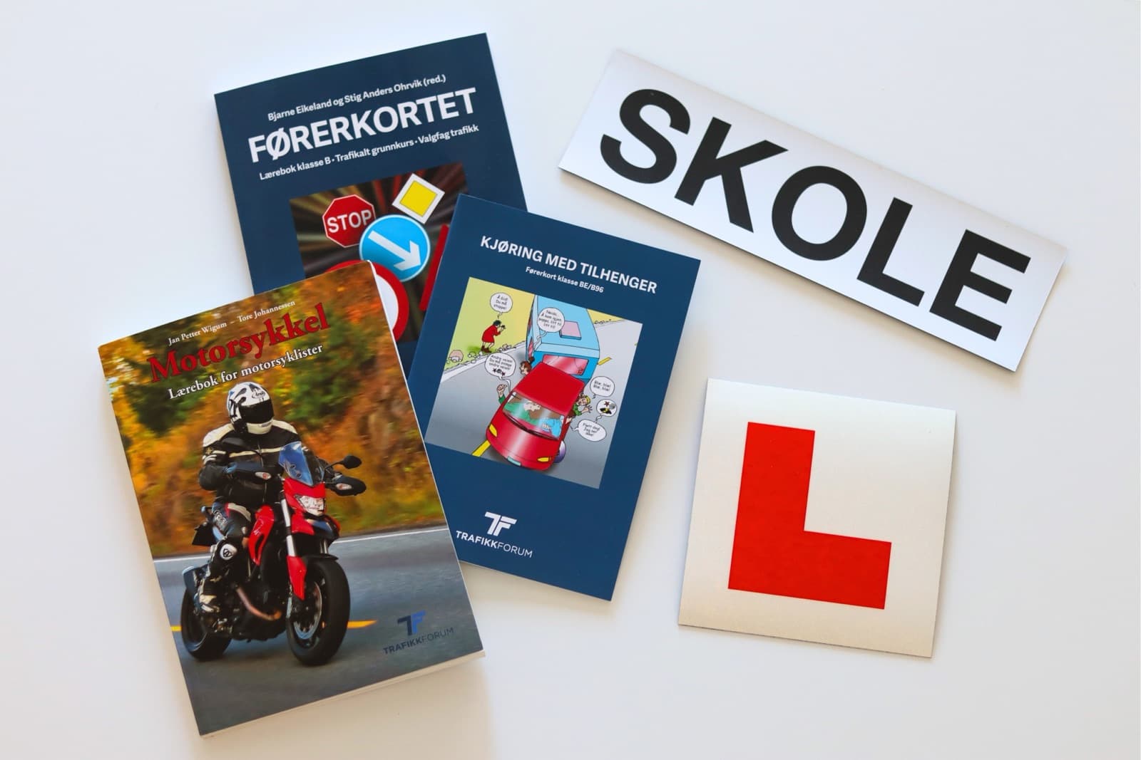 Lærebøker fra Trafikkforum sammen med et SKOLE-skilt og en L-plate